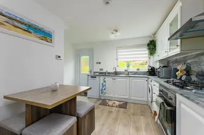 a kitchen with white cabinets and a wooden table at Comfortable & cozy Home Stay in East Kilbride