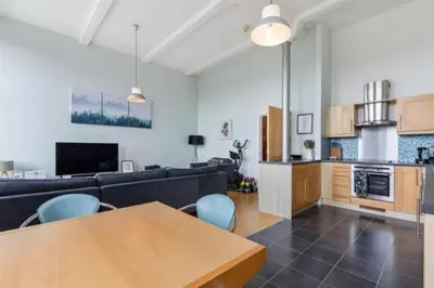 a living room with a couch and a table and a kitchen at Quay Glasgow Duplex apartment in Glasgow
