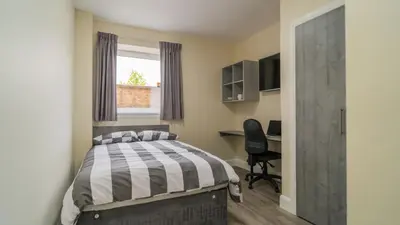 a bedroom with a bed and a desk and a window at SOAB Residence in Hamilton