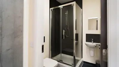 a bathroom with a shower and a toilet and a sink at SOAB Residence in Hamilton