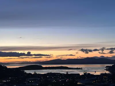 a sunset over a city and a body of water at Spacious 4BD Home with Stunning Oban Views in Oban