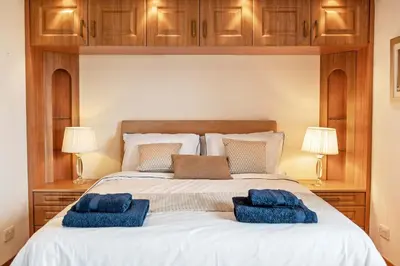 a bedroom with a large bed with blue pillows on it at Spacious 4BD Home with Stunning Oban Views in Oban