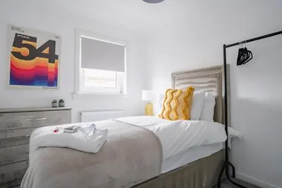 a white bedroom with a large bed with yellow pillows at 3 BDR House By Caledonia Luxe Stays Short Lets & Serviced Accommodation West Calder in West Calder