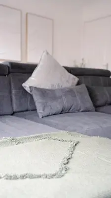 a couch with a pillow and a white rug at 3 BDR House By Caledonia Luxe Stays Short Lets & Serviced Accommodation West Calder in West Calder
