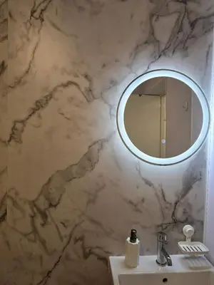 a bathroom with a marble wall with a mirror at Castle View Central Flat in Edinburgh