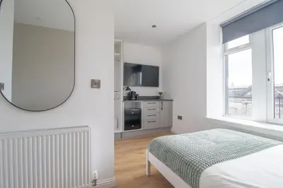 a white bedroom with a bed and a window at Alexandra Apartment in Falkirk