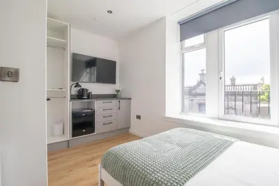 a white bedroom with a bed and a large window at Alexandra Apartment in Falkirk