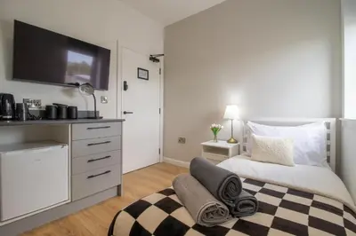 a bedroom with a bed with a tv on the wall at Alexandra Apartment in Falkirk