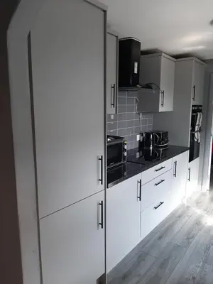 a kitchen with white cabinets and black counter tops at Newly renovated & furnished luxury bedroom in Kirkliston