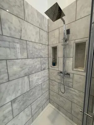 a bathroom with a shower with gray tiles at Limefield Mansion House in Livingston