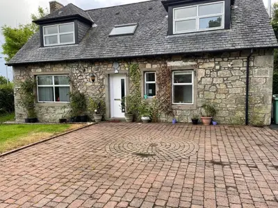 a stone house with a brick driveway in front of it at The Stables in Symington in Symington