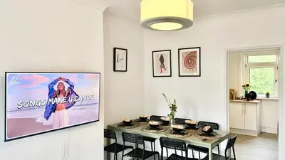 a dining room with a table and a tv on a wall at New quite and comfy home Glasgow in Knightswood