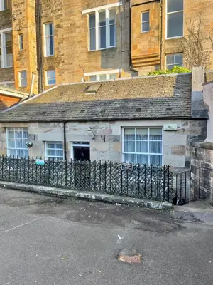an old building with a fence in front of a building at Little West End cottage in Edinburgh