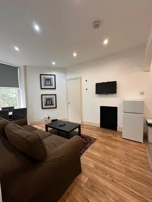 a living room with a couch and a tv on a wall at Caledonian Apartment in Edinburgh