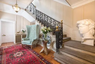 a living room with a staircase with a bust on the wall at Blossom Mansion in Edinburgh