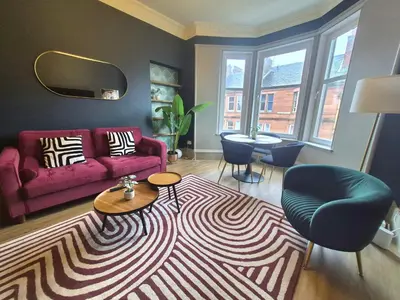 a living room with a red couch and a rug at Townhead Jewel by Coorie Doon Stays in Paisley