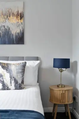 a bedroom with a bed and a table with a lamp at Riverside City Apartment in Glasgow