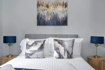 a bed with two lamps and a painting on the wall at Riverside City Apartment in Glasgow