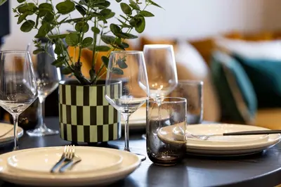 a table with glasses and plates and a vase with a plant at Luxury Refurbished City Retreat in Glasgow