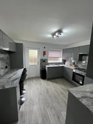 a large kitchen with gray cabinets and marble counter tops at Newly refurbed 3 bed home 15mins to Edin city in Livingston