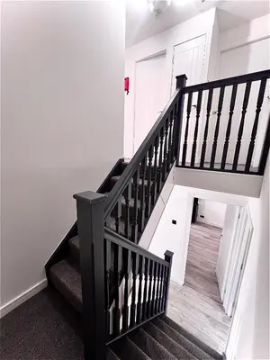 a staircase with black railings and white walls at Newly refurbed 3 bed home 15mins to Edin city in Livingston