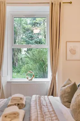 a bedroom with a window and a bed with towels at The Compact Caledonian Flat - Haymarket in Edinburgh