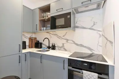 a white kitchen with a sink and a microwave at The Compact Caledonian Flat - Haymarket in Edinburgh