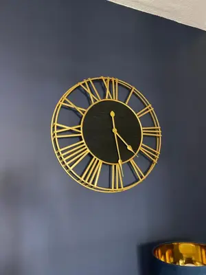 a gold and black clock on a blue wall at Grey Gables Cottage, Brodick, Isle of Arran, Scotland in Isle of Arran