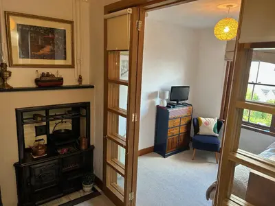 a living room with a fireplace and a television at Grey Gables Cottage, Brodick, Isle of Arran, Scotland in Isle of Arran
