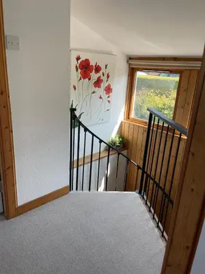 a stairway with a flower painting on the wall and a window at Grey Gables Cottage, Brodick, Isle of Arran, Scotland in Isle of Arran