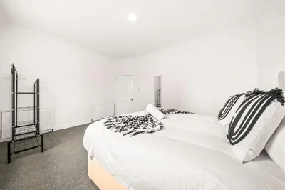 a white bed with black and white pillows on it at Cosy and Bright 3-Bedroom Flat in Glasgow
