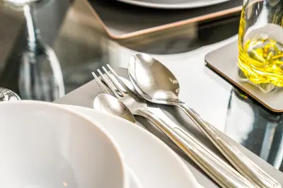 a table topped with white plates and silver utensils at Cosy and Bright 3-Bedroom Flat in Glasgow
