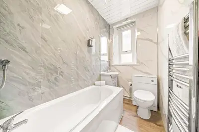 a white bathroom with a tub and a toilet at Cosy and Bright 3-Bedroom Flat in Glasgow
