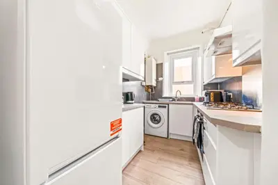 a kitchen with white cabinets and a washer and dryer at Cosy and Bright 3-Bedroom Flat in Glasgow