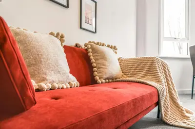 a red couch with pillows on it in a living room at Cosy and Bright 3-Bedroom Flat in Glasgow