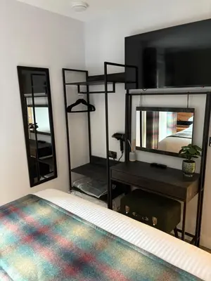 a bedroom with a bed and a desk with a mirror at The Wee Bothy in Oban