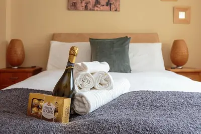 a bottle of champagne and towels on a bed at Free Parking - City Centre - 3 Bedrooms - 5 Guests in Edinburgh