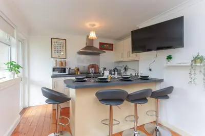 a kitchen with a counter with four stools in it at Free Parking - City Centre - 3 Bedrooms - 5 Guests in Edinburgh