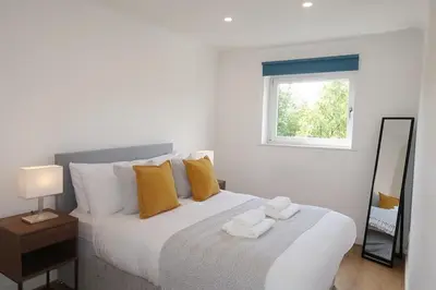 a bedroom with a large white bed with yellow pillows at Spacious 2 Bed Apartment Near Glasgow Airport in Glasgow