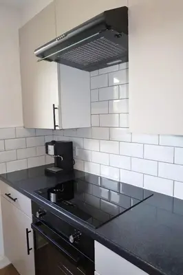 a kitchen with a black counter top and white cabinets at Spacious 2 Bed Apartment Near Glasgow Airport in Glasgow