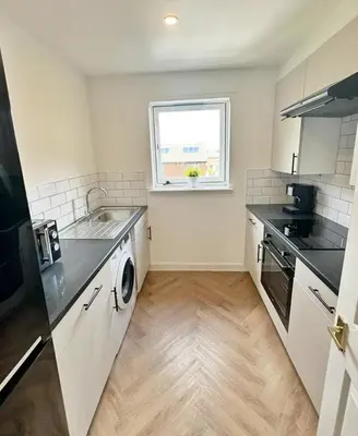 a white kitchen with a sink and a window at Spacious 2 Bed Apartment Near Glasgow Airport in Glasgow