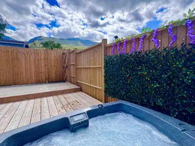 a hot tub in a backyard with a fence at 60 Mile Inn - Luxury Pods with Hot Tubs in Bridge of Orchy