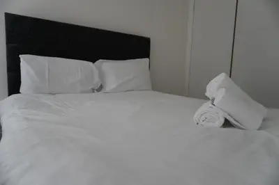 a white bed with a roll of towels on it at Glasgow Group Getaway in Glasgow