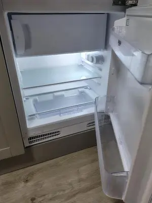 an empty refrigerator with its door open on a wooden floor at Millburn Chalet in Inverkip