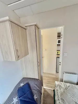 a small bedroom with a bed and a cupboard at Four-bed Delta Caravan, Uddingston, Glasgow Located in Uddingston, Glasgow at Maryville Caravan Site in Uddingston
