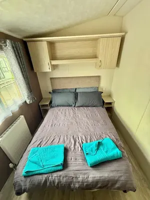 a bed in a small room with blue pillows on it at Four-bed Delta Caravan, Uddingston, Glasgow Located in Uddingston, Glasgow at Maryville Caravan Site in Uddingston