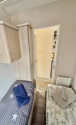 a small bedroom with a bed and a mirror at Four-bed Delta Caravan, Uddingston, Glasgow Located in Uddingston, Glasgow at Maryville Caravan Site in Uddingston