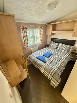 a small bedroom with a bed with blue towels on it at Deluxe Delta 4-Bedroom Caravan Located at Maryville Caravan Site Uddingston, Glasgow in Uddingston