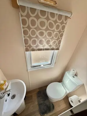 a bathroom with a toilet and a sink and a window at Deluxe Delta 4-Bedroom Caravan Located at Maryville Caravan Site Uddingston, Glasgow in Uddingston