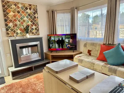 a living room with a couch and a fireplace at Deluxe Delta 4-Bedroom Caravan Located at Maryville Caravan Site Uddingston, Glasgow in Uddingston